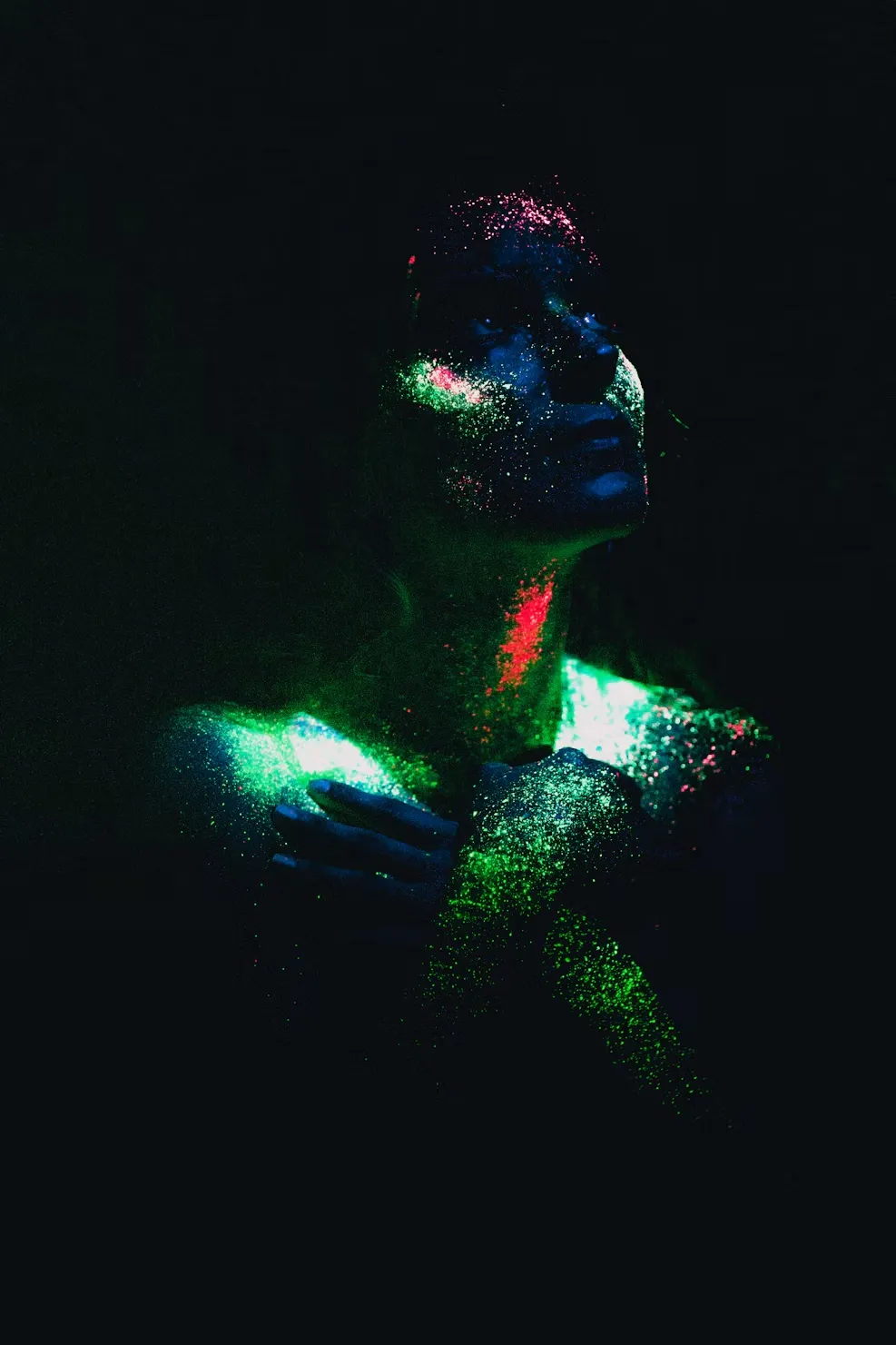 Rostro y hombros cubiertos de pintura neón que brilla con luz negra