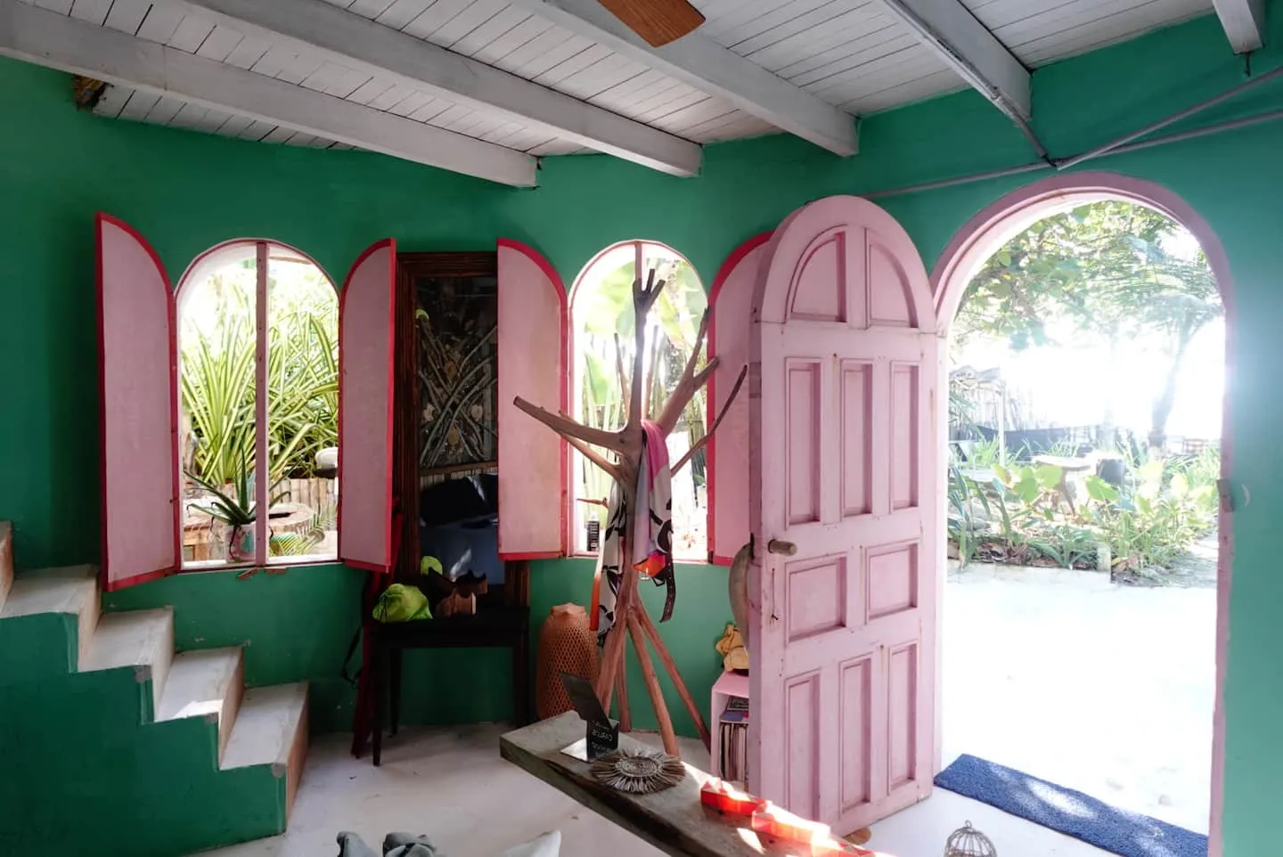 Habitación verde que abre al jardín por una puerta rosada